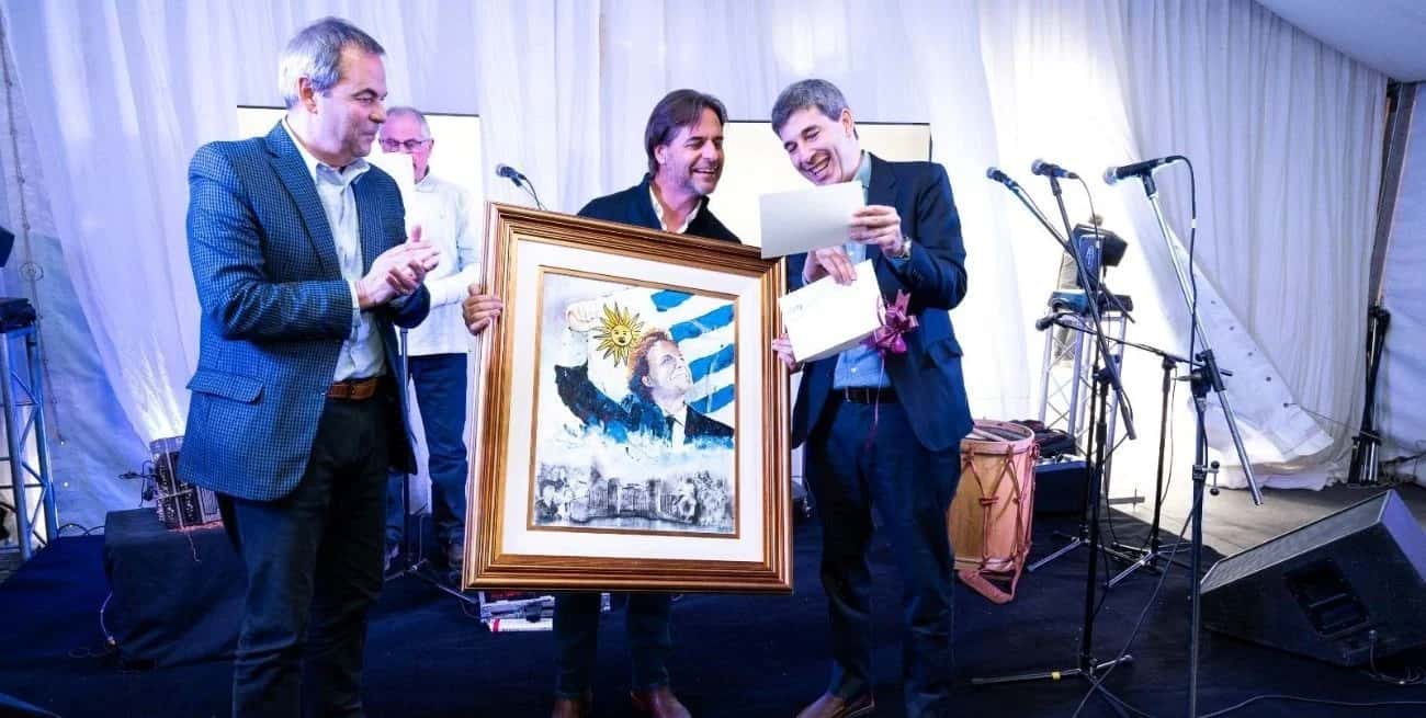 El presidente del Grupo Sancor Seguros, Gustavo Badosa (izquierda) y el CEO, Alejandro Simón (derecha), entregaron una pintura obsequio al presidente Lacalle Pou. Créditos: Gentileza