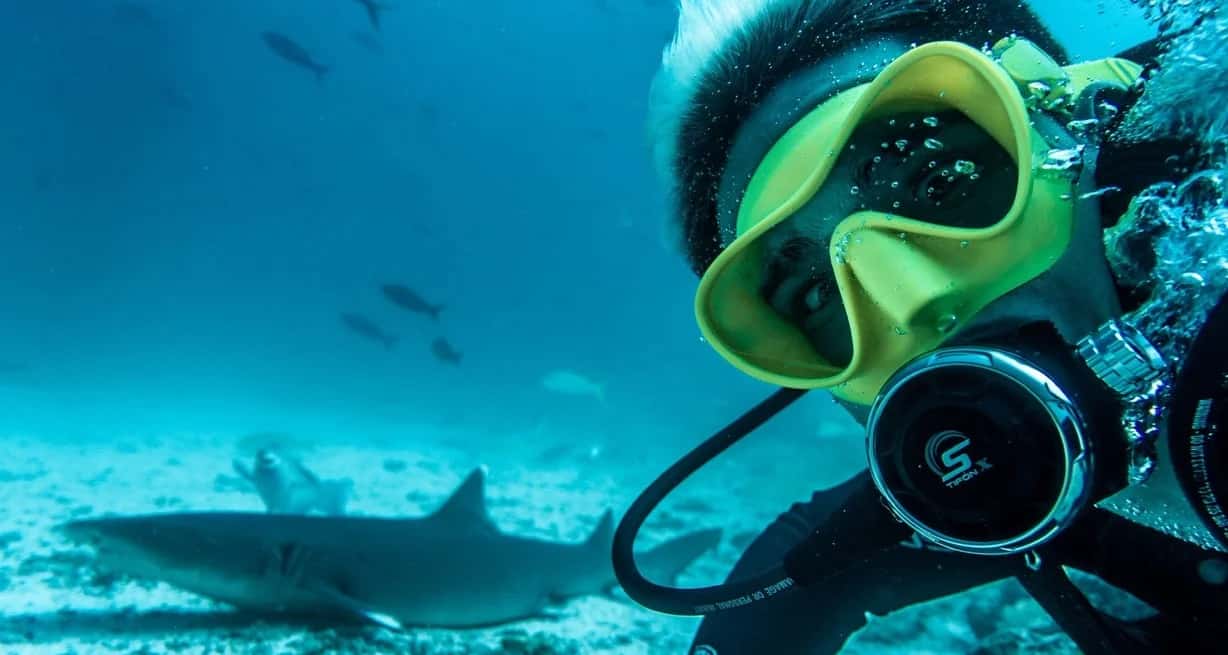 Nicolás Marin en el fondo del océano nadando junto a un tiburón.